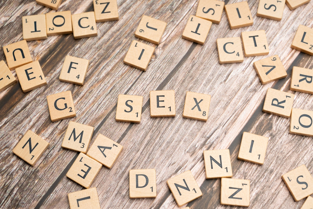 scrabble tiles spelling out the word sex on a wooden table